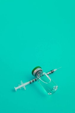 Yeşil zemin üzerinde ilaç bulunan şırınga ampulü