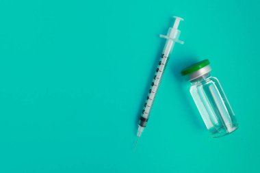 Yeşil zemin üzerinde ilaç bulunan şırınga ampulü