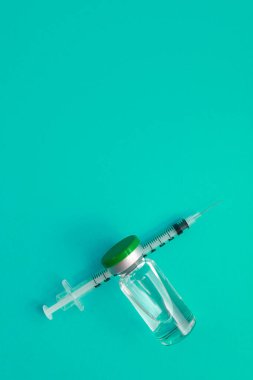 Yeşil zemin üzerinde ilaç bulunan şırınga ampulü