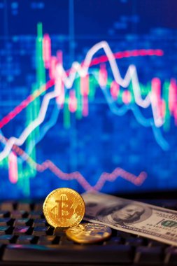 Grafiklerin arkaplanındaki bir bilgisayar klavyesinde kum saati, dolar ve bitcoin 'ler