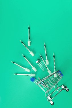 Yeşil zemin üzerinde şırınga ve ampul bulunan süpermarket tramvayı