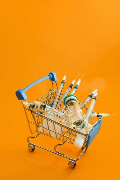 Тележка Супермаркета Шприцами Ампулами Оранжевом Фоне — стоковое фото