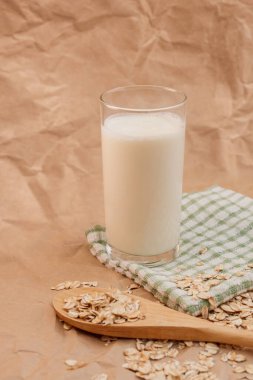 Bir bardak süt ve yulaf ezmeli ahşap kaşık.