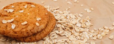 Panaramnom arka planına saçılmış yulaf ezmeli kurabiye ve yulaf ezmesi.