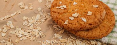 Panaramnom arka planına saçılmış yulaf ezmeli kurabiye ve yulaf ezmesi.