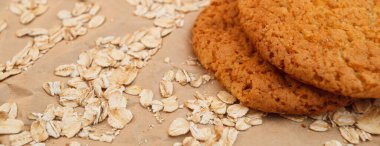 Panaramnom arka planına saçılmış yulaf ezmeli kurabiye ve yulaf ezmesi.