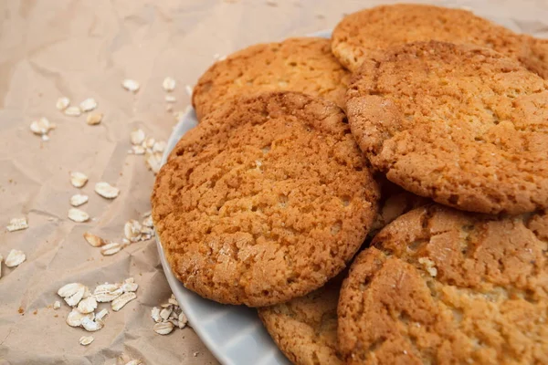 oatmeal cookies and scattered oatmeal on crumpled paper background