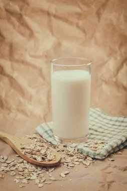 Bir bardak süt ve yulaf ezmeli ahşap kaşık.