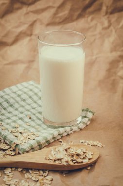 Bir bardak süt ve yulaf ezmeli ahşap kaşık.