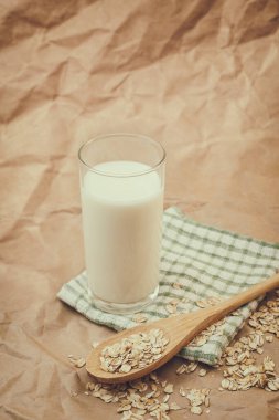 Bir bardak süt ve yulaf ezmeli ahşap kaşık.