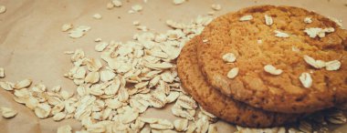 Panaramnom arka planına saçılmış yulaf ezmeli kurabiye ve yulaf ezmesi.