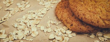 Panaramnom arka planına saçılmış yulaf ezmeli kurabiye ve yulaf ezmesi.