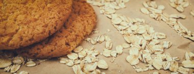 Panaramnom arka planına saçılmış yulaf ezmeli kurabiye ve yulaf ezmesi.