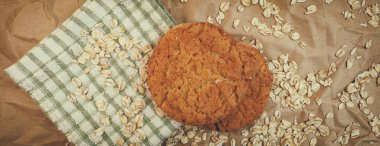 Panaramnom arka planına saçılmış yulaf ezmeli kurabiye ve yulaf ezmesi.