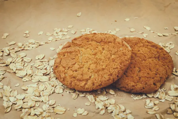 oatmeal cookies and scattered oatmeal on crumpled paper background