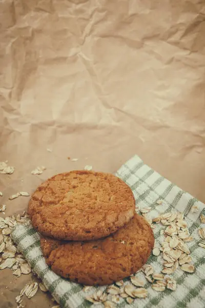 oatmeal cookies and scattered oatmeal on crumpled paper background