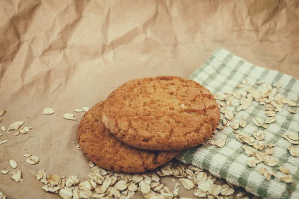 oatmeal cookies and scattered oatmeal on crumpled paper background