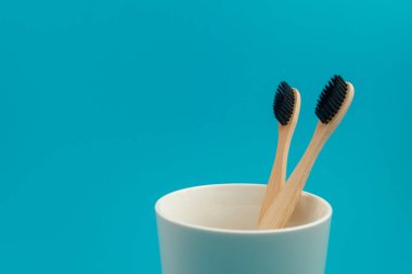 Bardaktaki mavi arka planda ahşap diş fırçası