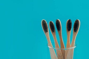 Bardaktaki mavi arka planda ahşap diş fırçası