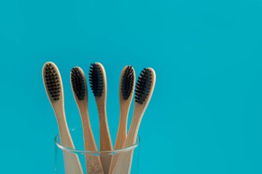 Bardaktaki mavi arka planda ahşap diş fırçası