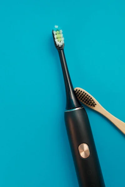 Mavi arka planda elektrikli ve ahşap diş fırçası