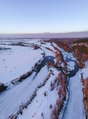 Orman ve donmuş nehir baharda, güneşin batışında erimiş yamalar gibi görünen, Rusya 'da hala kar varken.