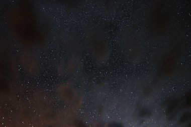Gece gökyüzündeki yıldızlar bir yaz gecesinde bulutlar arasında