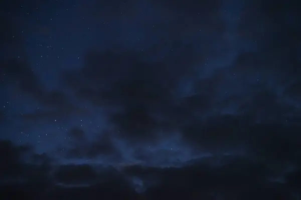 Gece gökyüzündeki yıldızlar bir yaz gecesinde bulutlar arasında