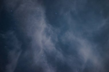 Bir yaz gecesinde bulutların arasından gökyüzünde yıldızlar. Gece gökyüzünde ay ışığıyla aydınlanan bulutların arasında yıldızlar.