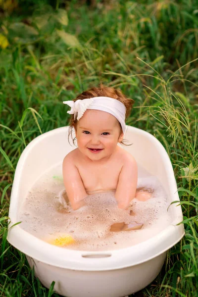 幸せな幼児は面白い笑顔で屋外の浴槽に座っています 背景に緑の草 子供時代の世話 自然とのつながり そして瞬間のコンセプトを楽しむ — ストック写真
