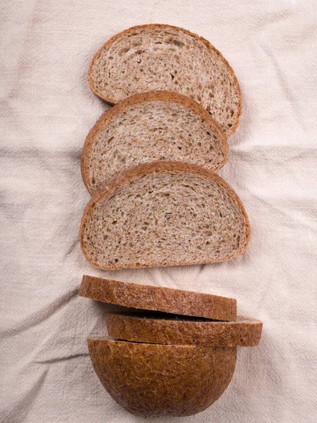 灰色の背景に古い木のトレイに小麦粉と自家製の白黒小麦パンをスライス トップ表示 — ストック写真