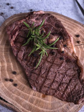 Sous-vide ızgara biftek ve ahşap tabakta dökme demir tavada otlar. Kopyalama alanı olan gri arkaplan