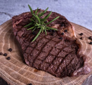 Sous-vide ızgara biftek ve ahşap tabakta dökme demir tavada otlar. Kopyalama alanı olan gri arkaplan