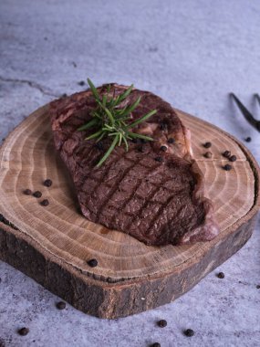 Sous-vide ızgara biftek ve ahşap tabakta dökme demir tavada otlar. Kopyalama alanı olan gri arkaplan