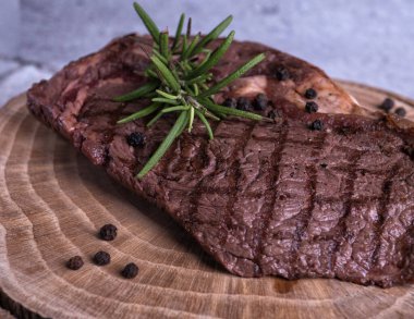 Sous-vide ızgara biftek ve ahşap tabakta dökme demir tavada otlar. Kopyalama alanı olan gri arkaplan