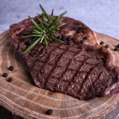 Sous-vide ızgara biftek ve ahşap tabakta dökme demir tavada otlar. Kopyalama alanı olan gri arkaplan