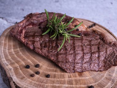 Sous-vide ızgara biftek ve ahşap tabakta dökme demir tavada otlar. Kopyalama alanı olan gri arkaplan