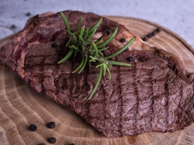 Sous-vide ızgara biftek ve ahşap tabakta dökme demir tavada otlar. Kopyalama alanı olan gri arkaplan