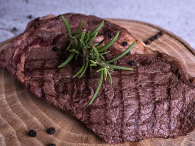 Sous-vide ızgara biftek ve ahşap tabakta dökme demir tavada otlar. Kopyalama alanı olan gri arkaplan