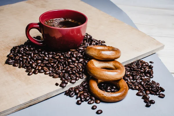 Grãos de café e xícara vermelha em madeira — Fotografia de Stock