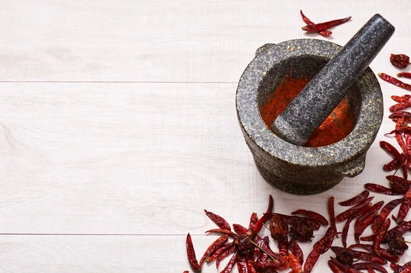 Pestle with mortar, surrounded by dried chili and habanero peppers — Stock Photo, Image