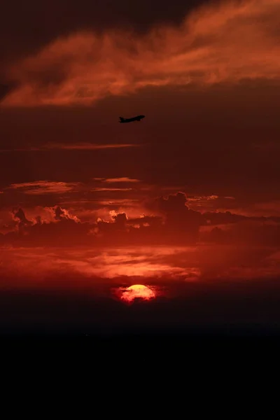 飛行機は赤い空と美しい夕日を背景に離陸します 太陽の上の航空機のシルエット — ストック写真