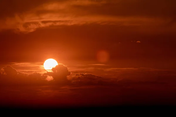 雲の後ろにオレンジの夕日 太陽フレアと雲のシルエット — ストック写真