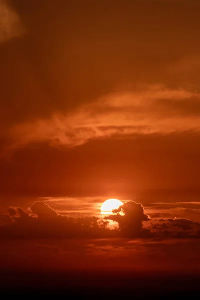 雲の後ろのオレンジ色の日没で太陽 雲の照明されたシルエット — ストック写真