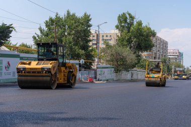 Almaty, Kazakistan - 17 Temmuz 2025: Asfalt yol silindirleri yeni bir yol boyunca yuvarlanıyor. Özel ekipmanlar