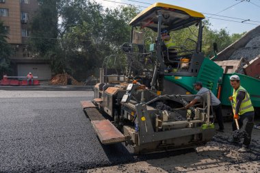 Almaty, Kazakistan - 17 Temmuz 2025: İşçiler yol boyunca asfalt kaldırımı işletiyorlar. Özel ekipmanlar
