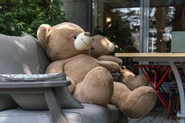 Almaty, Kazakistan - 17 Temmuz 2025: Doldurulmuş bir ayı kafeterya masasında oturuyor. Yaratıcı pazarlama