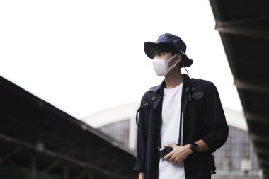 Covid-19 'u korumak için sağlık maskeli Asyalı gezginler ve kameralar tren istasyonunda. Yeni normal yaşam tarzı.