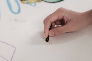 Çocuk beyaz kağıda boya kalemleriyle resim yapıyor..