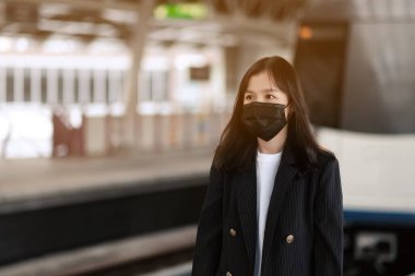 Tren istasyonunda yüz maskeli Asyalı ofis kadınları.
